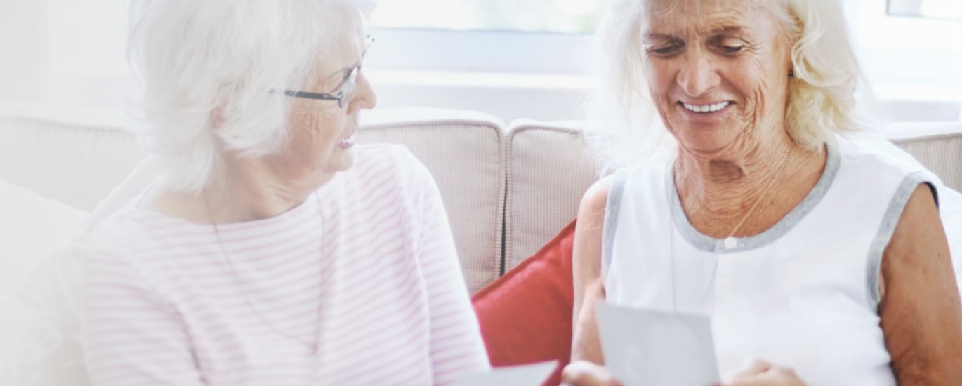 Two senior women sit together on a couch.