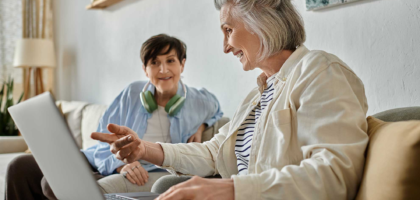 two senior women sit on the couch together
