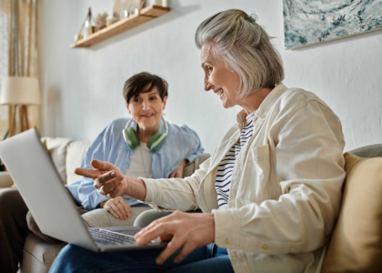 two senior women sit on the couch together