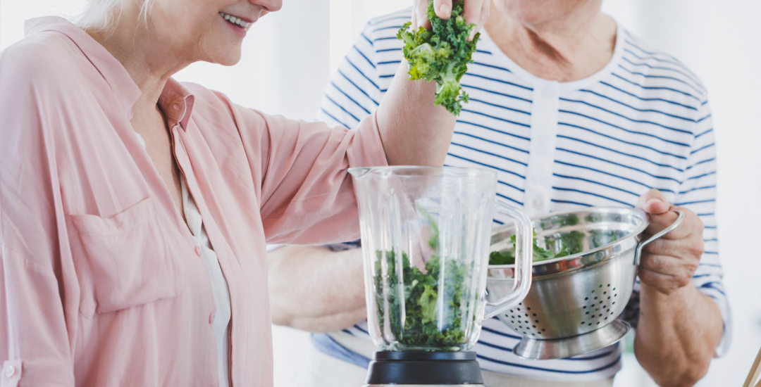 two seniors aging in place make a smoothie in their kitchen