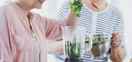 two seniors aging in place make a smoothie in their kitchen