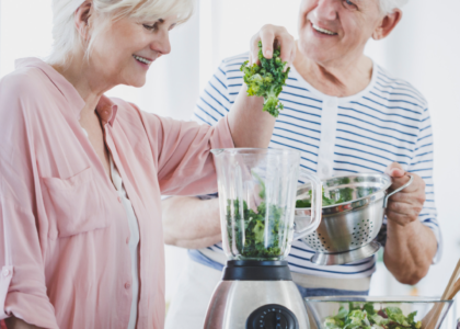 two seniors aging in place make a smoothie in their kitchen
