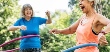 Two older women hula hoop together.