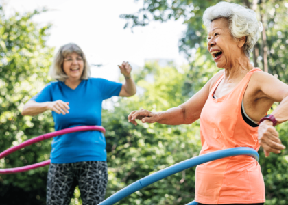 Two older women hula hoop together.