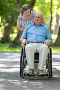Senior caregiver assisting an older man in a wheelchair outdoors during a walk in Scottsdale, AZ