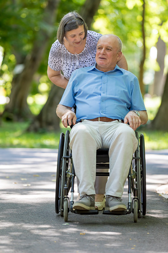 Senior caregiver assisting an older man in a wheelchair outdoors during a walk in Scottsdale, AZ